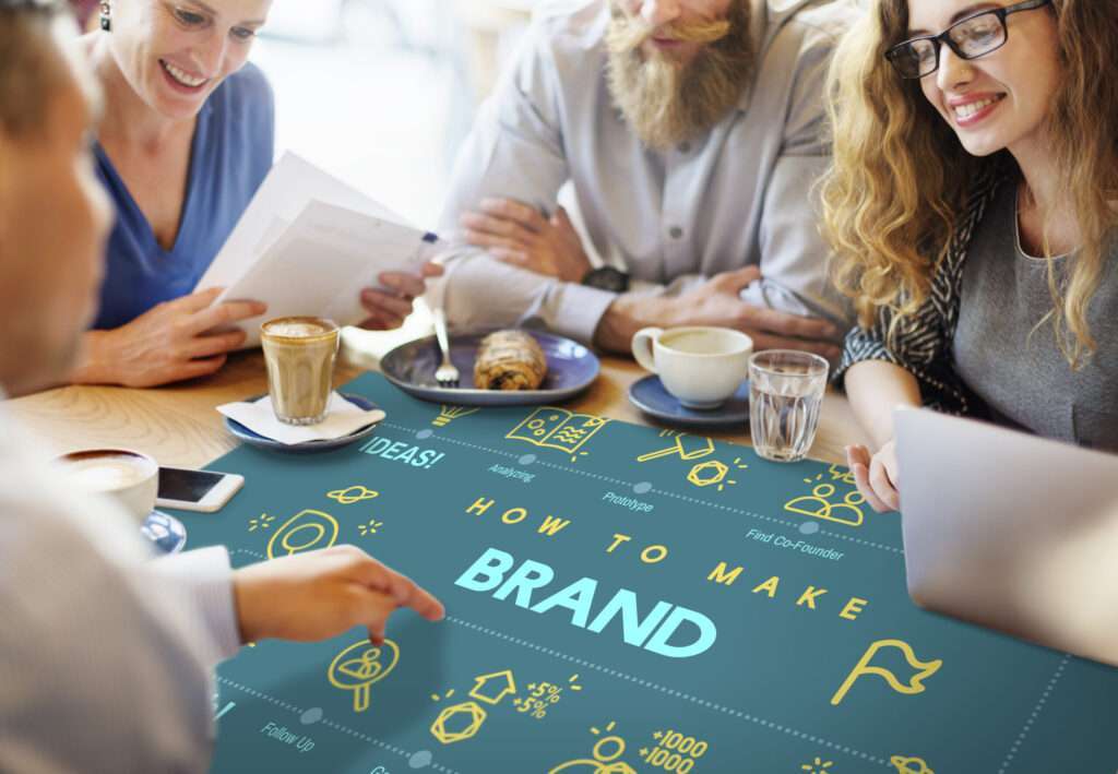 Group of people gathered around a table looking at text that says Brand